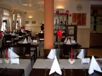 Gastraum des Gourmet mit weiß gedeckten Tischen und roten Blumen