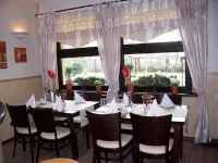 Restauranttische vor großen Fenstern mit Blumen auf den Tischen