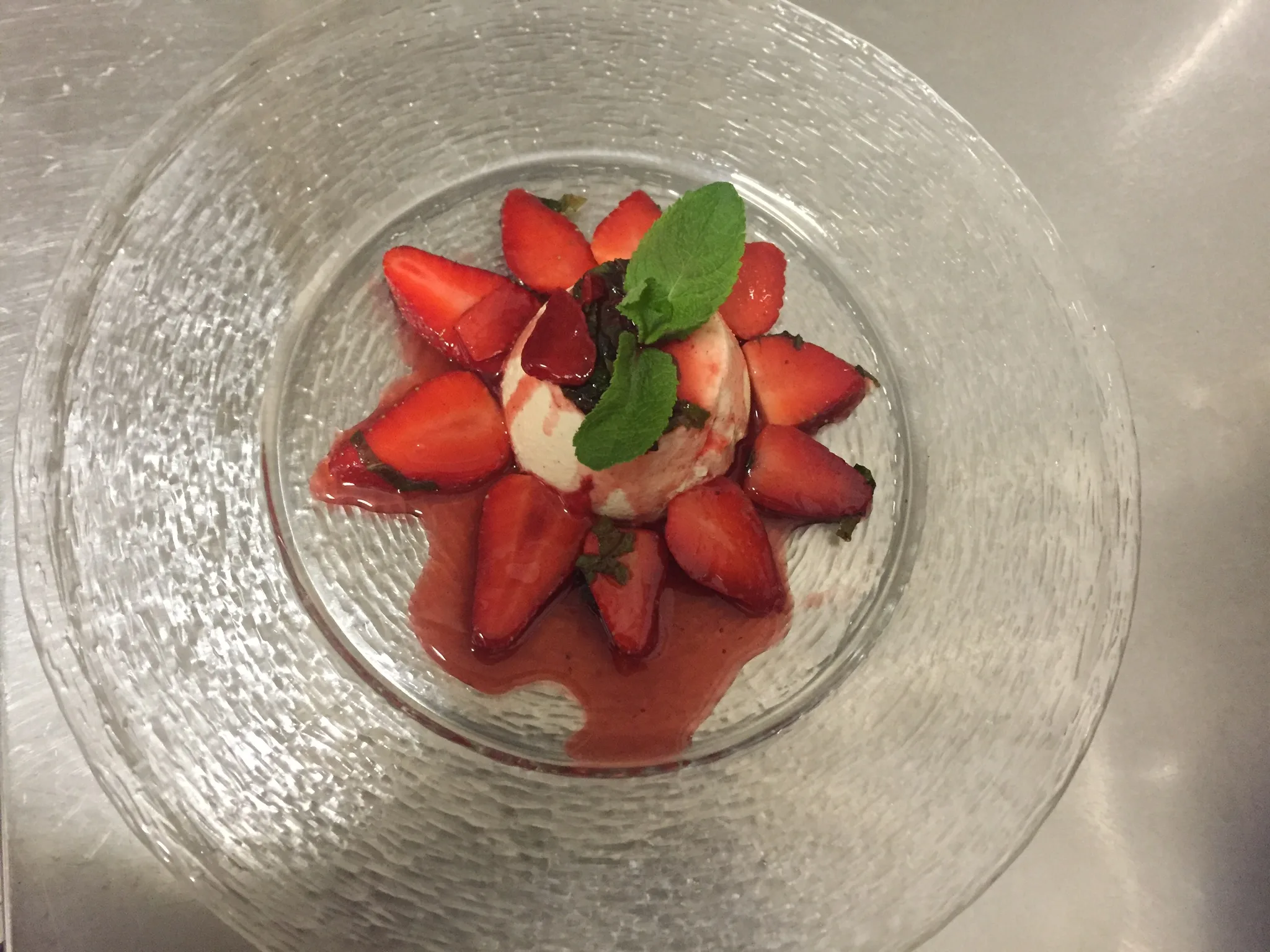 Dessert mit Erdbeeren, Creme und Minze in einem Glasteller