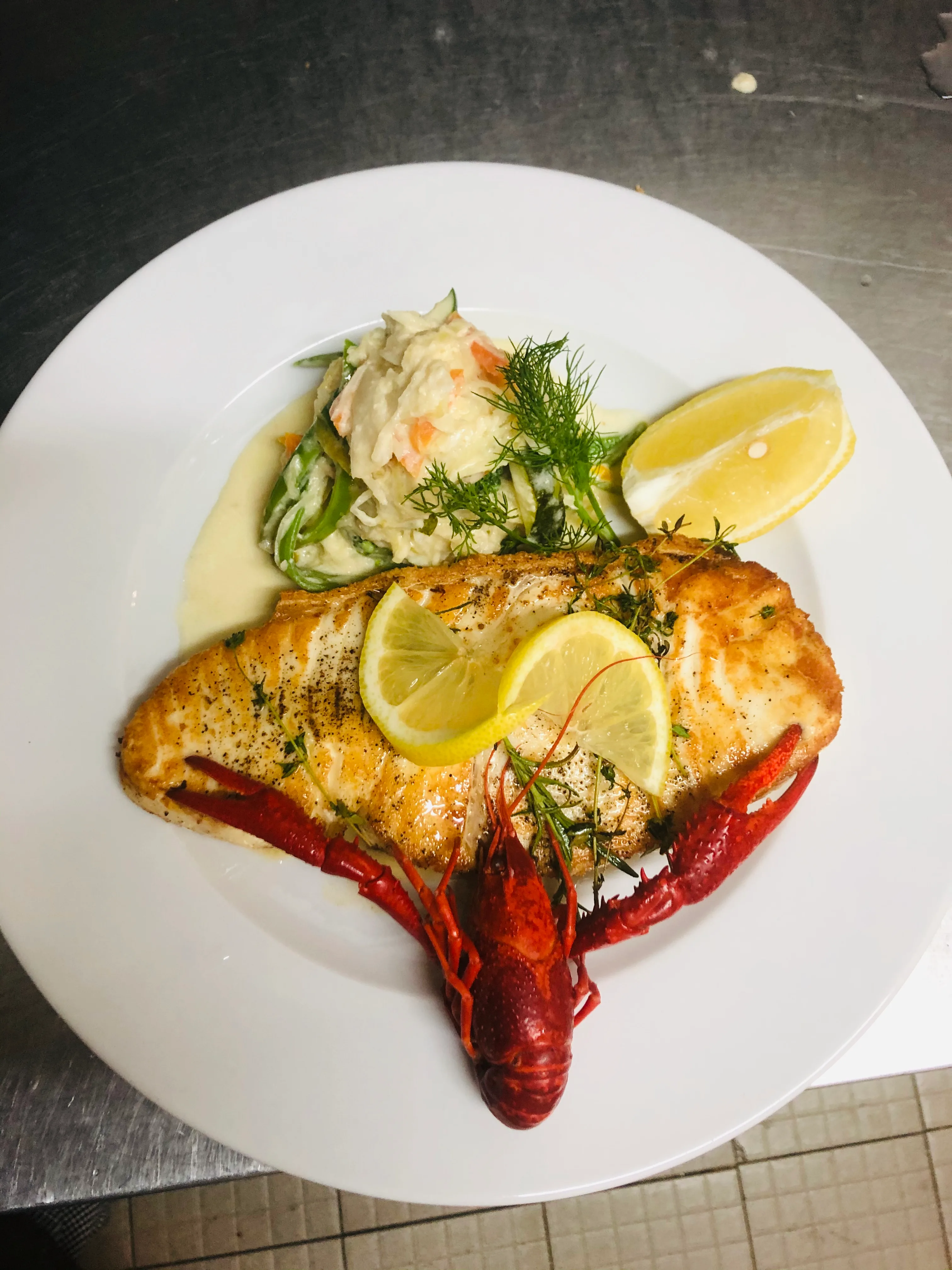 Gebratenes Fischfilet mit Flusskrebs, Gemüse und Zitronen