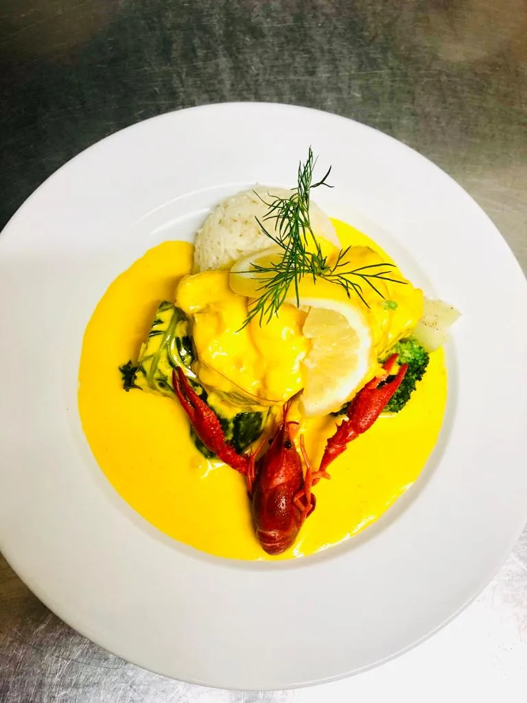 Fischgericht mit gelber Sauce, Reis, Gemüse und Flusskrebs